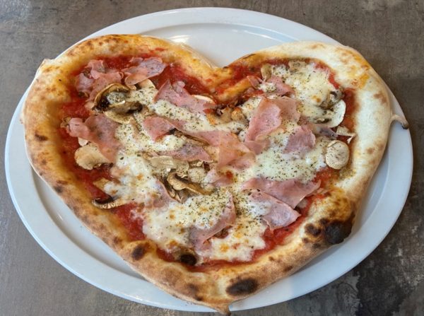 Pizza en forme de coeur avec du jambon et des champignons